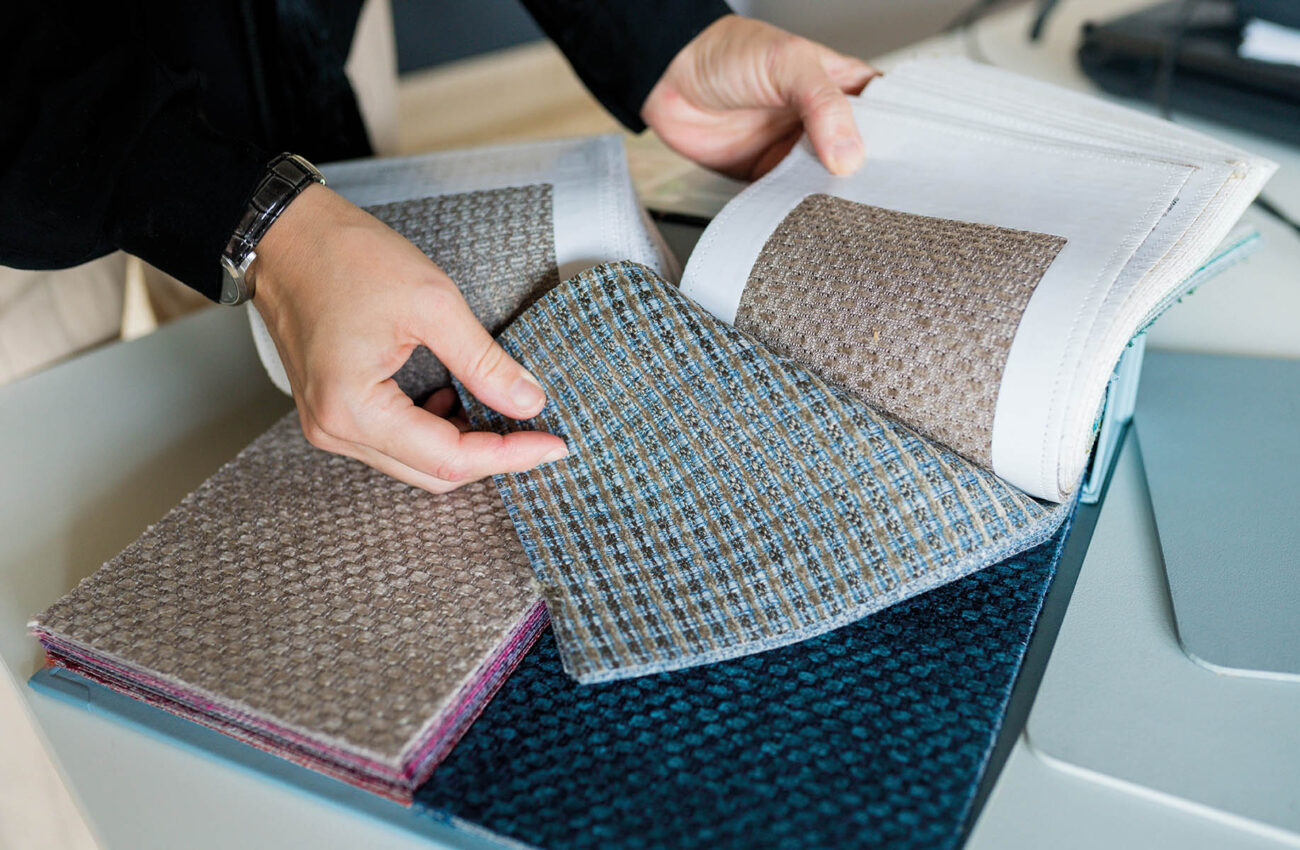 Close up woman choosing fabrics swatches for sofa in store. Inte